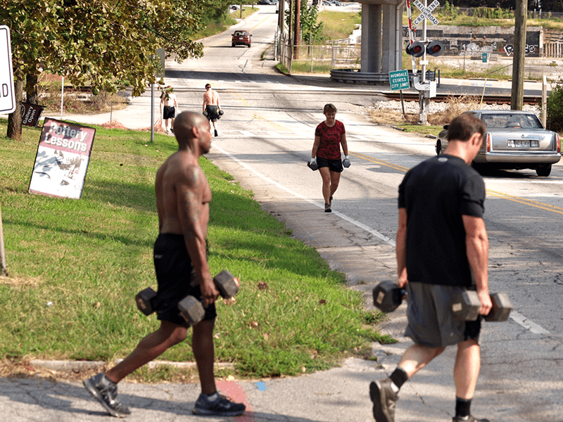 Crossfit grunt work male and female crossfitters farmer's carry exercise outside