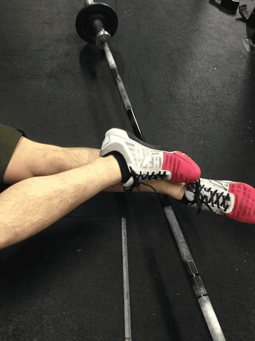 crossfit guy works on ankle mobility by rolling with a barbell