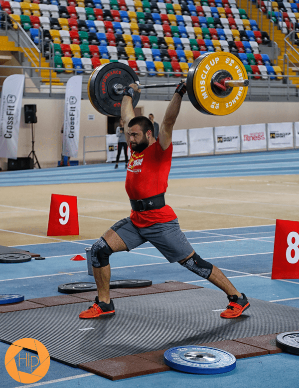 male crossfit athlete split jerk with barbell