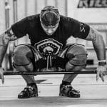 male crossfit athlete snatches barbell during intense crossfit conditioning eating clean