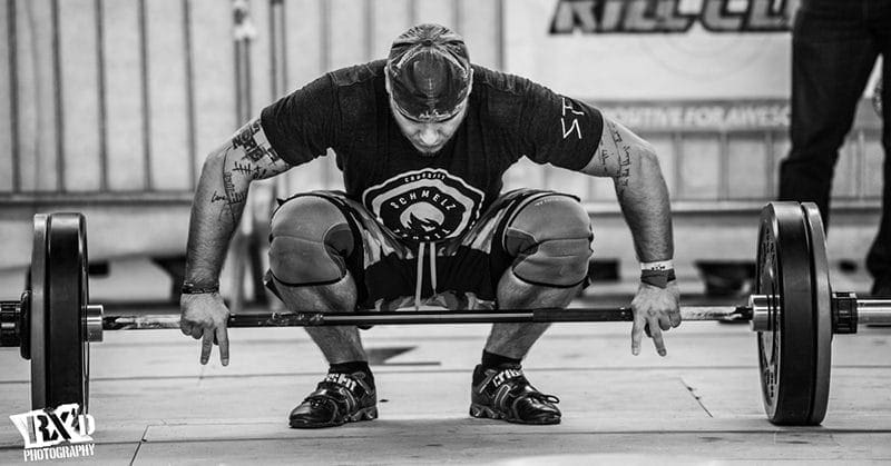 male crossfit athlete snatches barbell during intense crossfit conditioning eating clean