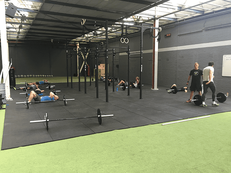 exhausted athletes lie on floor after workout at mobilis crossfit