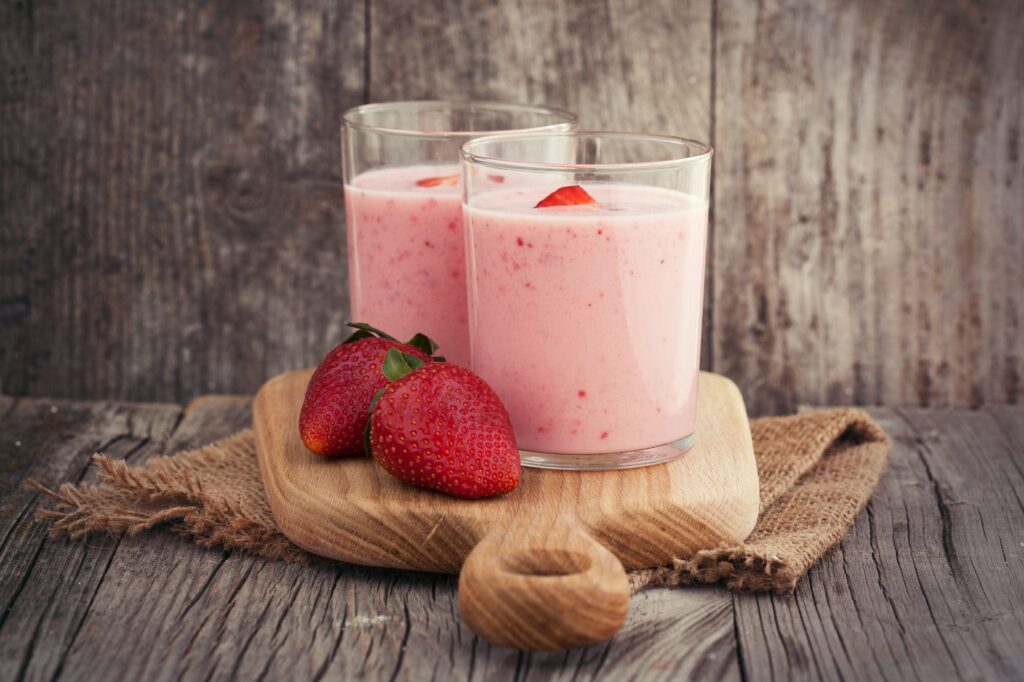 Fresh healthy strawberry smoothie on old wooden background