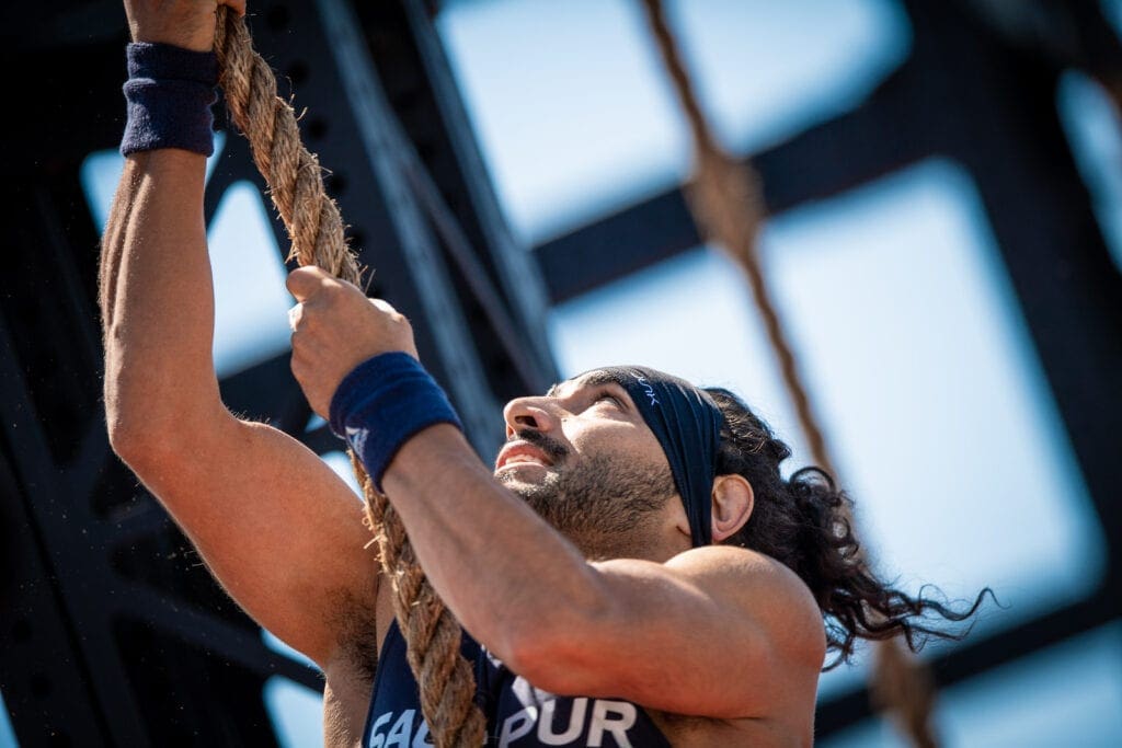 athlete performs rope climb workouts outdoors