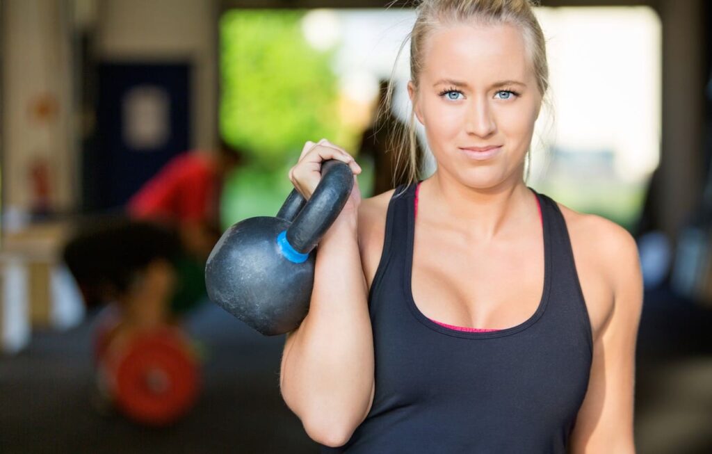 Foto de Female middle age fitness model shows muscular and lean arm  strength while performing a dumbbell curl in gym. do Stock