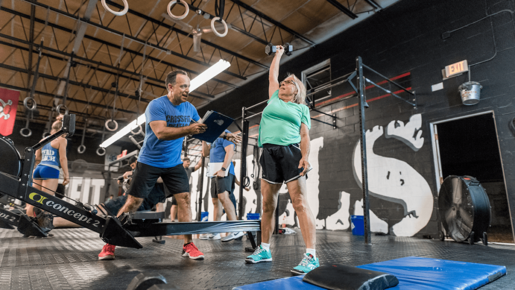 master athlete holds dumbbell overhead at training facility