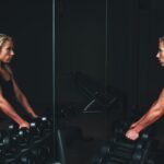 woman readies to perform dumbbell shrugs