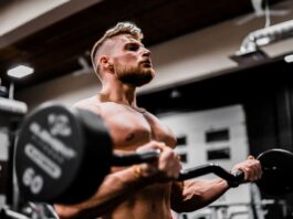 man trains powerbuilding with barbell curls
