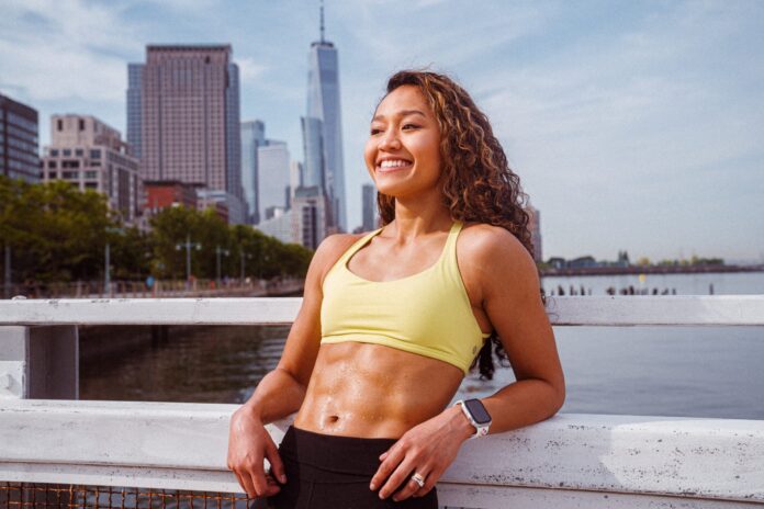 woman smiles in fitness gear with abs muscles