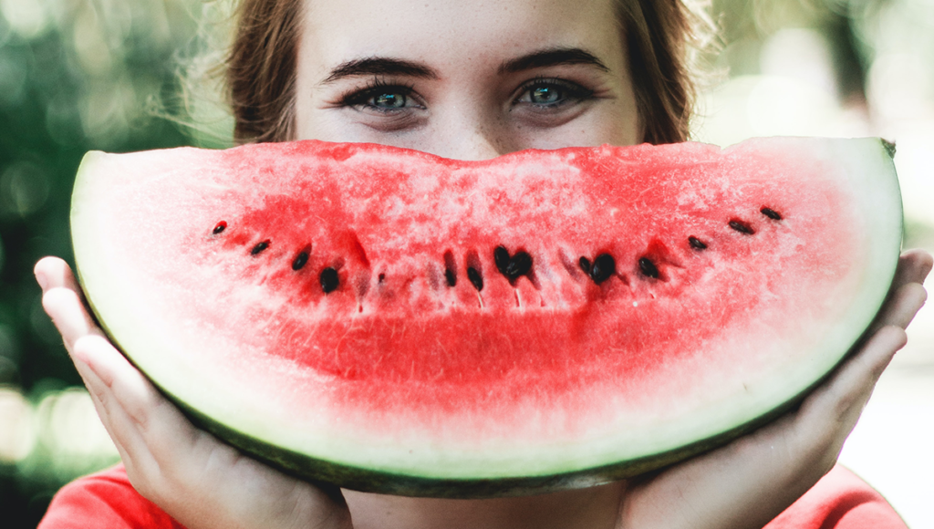 woman smiles energetically with watermelon