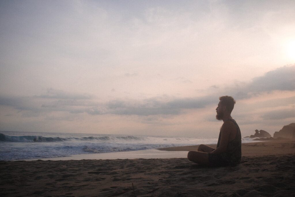 man practices meditation in the morning by beach