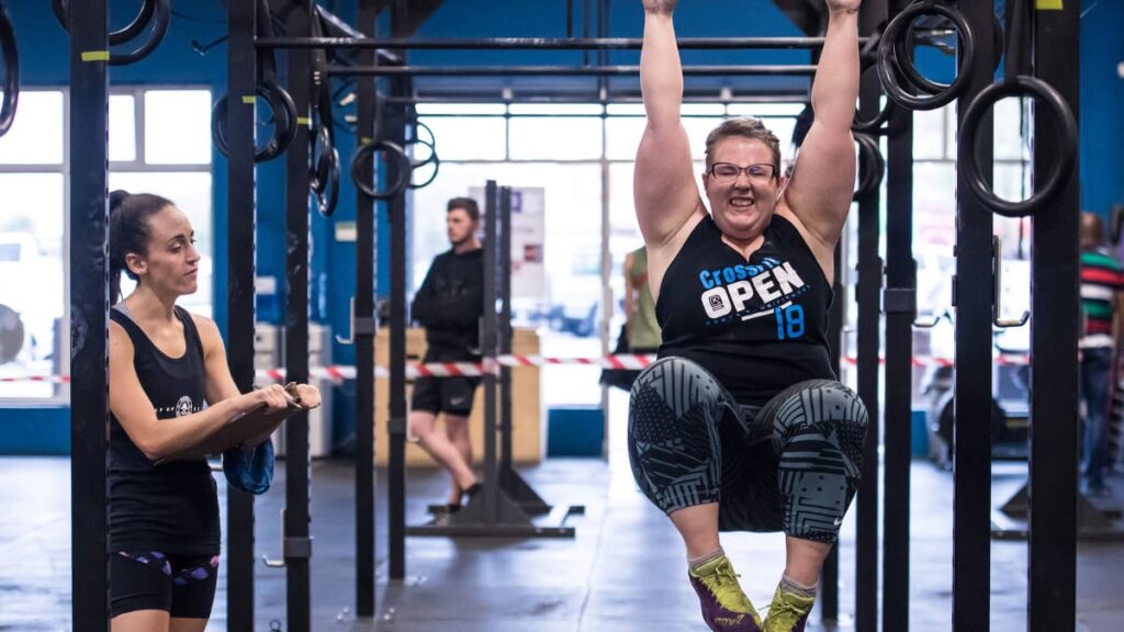 athlete does toes to barbell progression doing oblique knee raises exercise