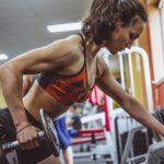 woman performs dumbbell row to grow muscle