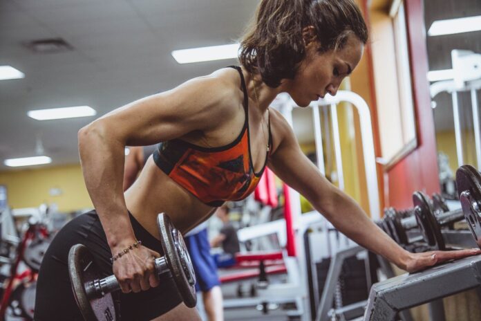woman performs dumbbell row to grow muscle