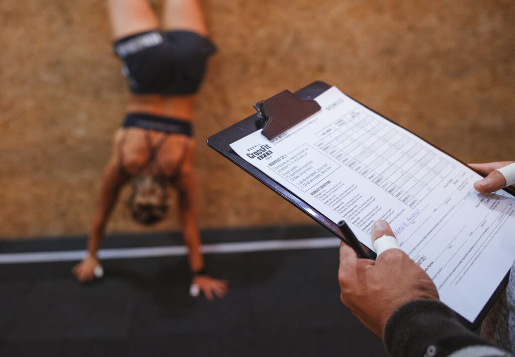 2022 crossfit open score card with athlete doing wall walk in background