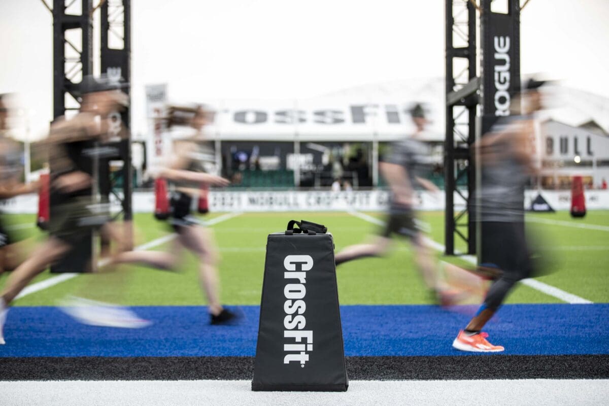 crossfit logo with team athletes running in blurred background