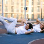 two women practice crunch variations for abs