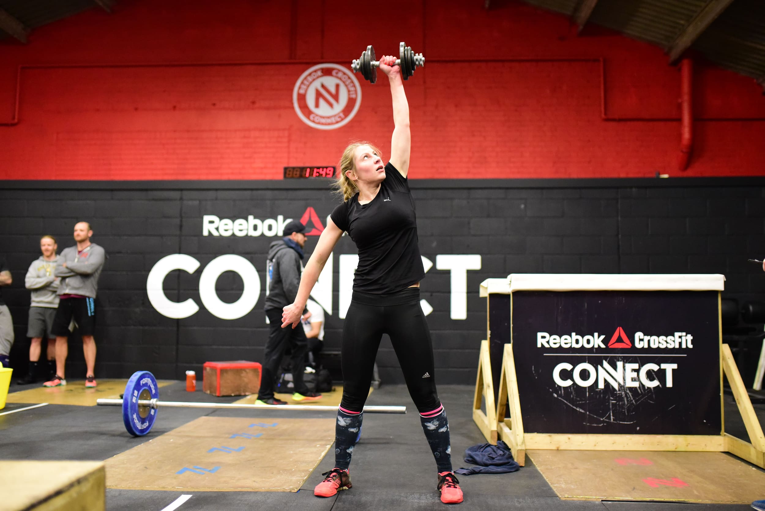crossfit community member performs dumbbell snatch