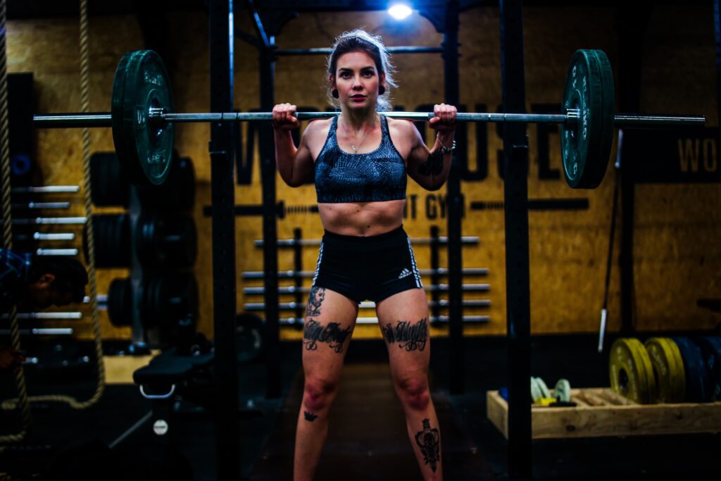 Woman rests between sets of back squats slow and fast reps for muscle growth