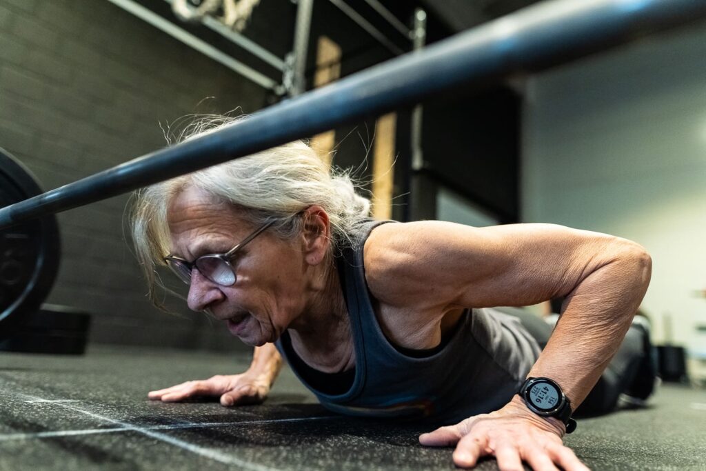 masters athlete performs a burpee over bar during CrossFit competition