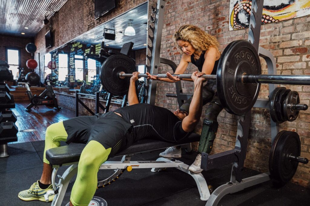 man sets up arch in the bench press with spotter behind