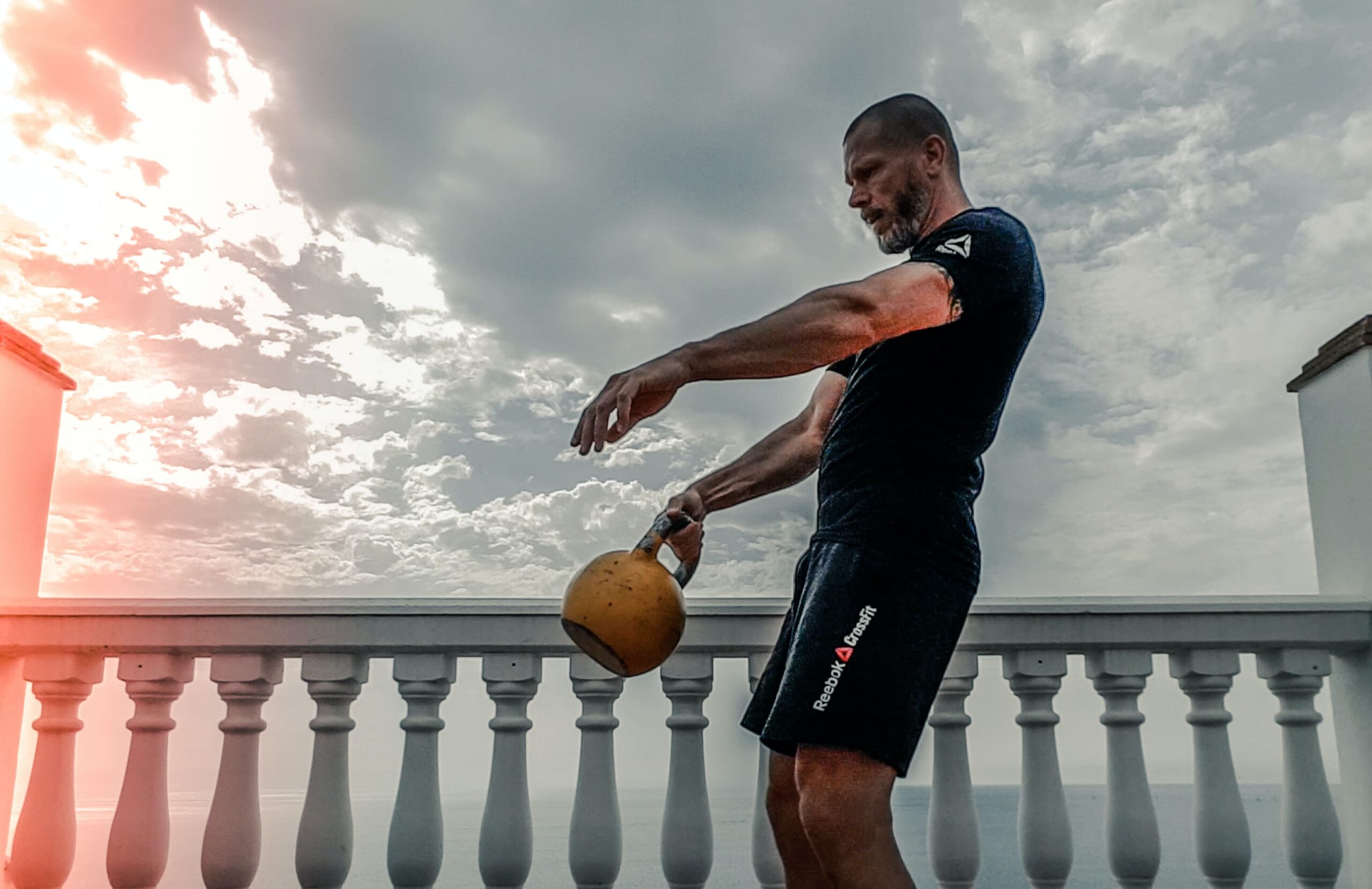 man performs kettlebell workout with single kettlebell