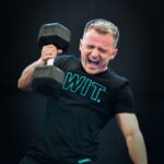 athlete perform dumbbell snatch against dark background